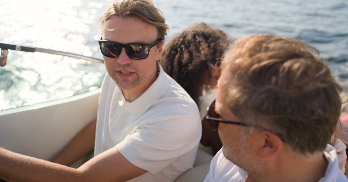 The captain talking with guests over the sunlit water