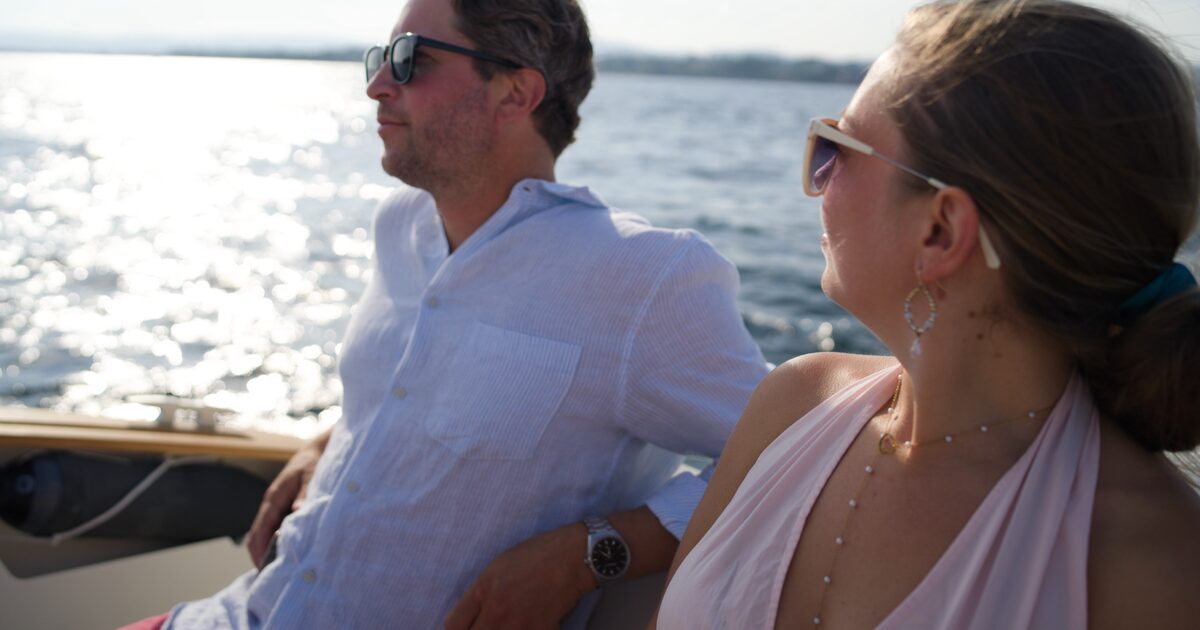 A couple close together at the rail over sparkling water