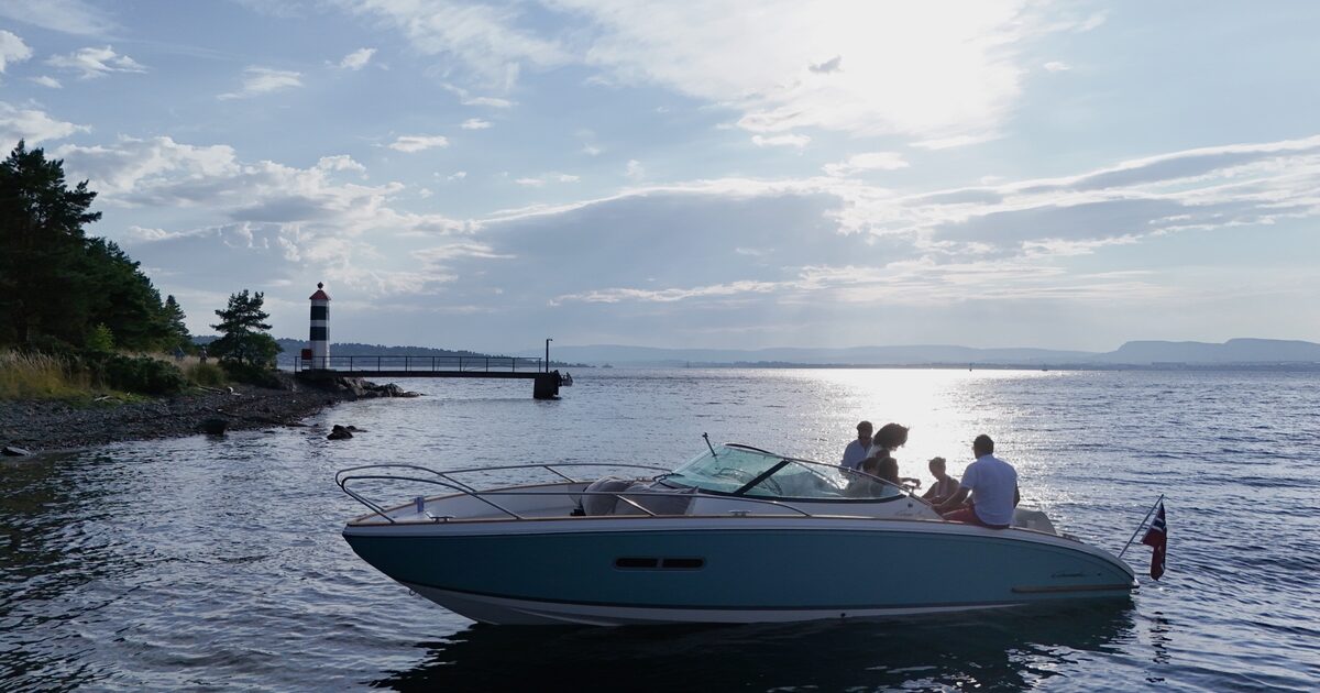 Guests looking out over the fjord by a lighthouse in evening light