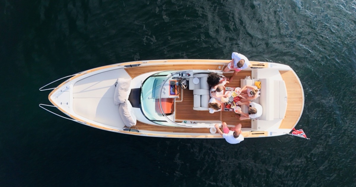 A family gathered around the food-laden teak table on deck, seen from directly above