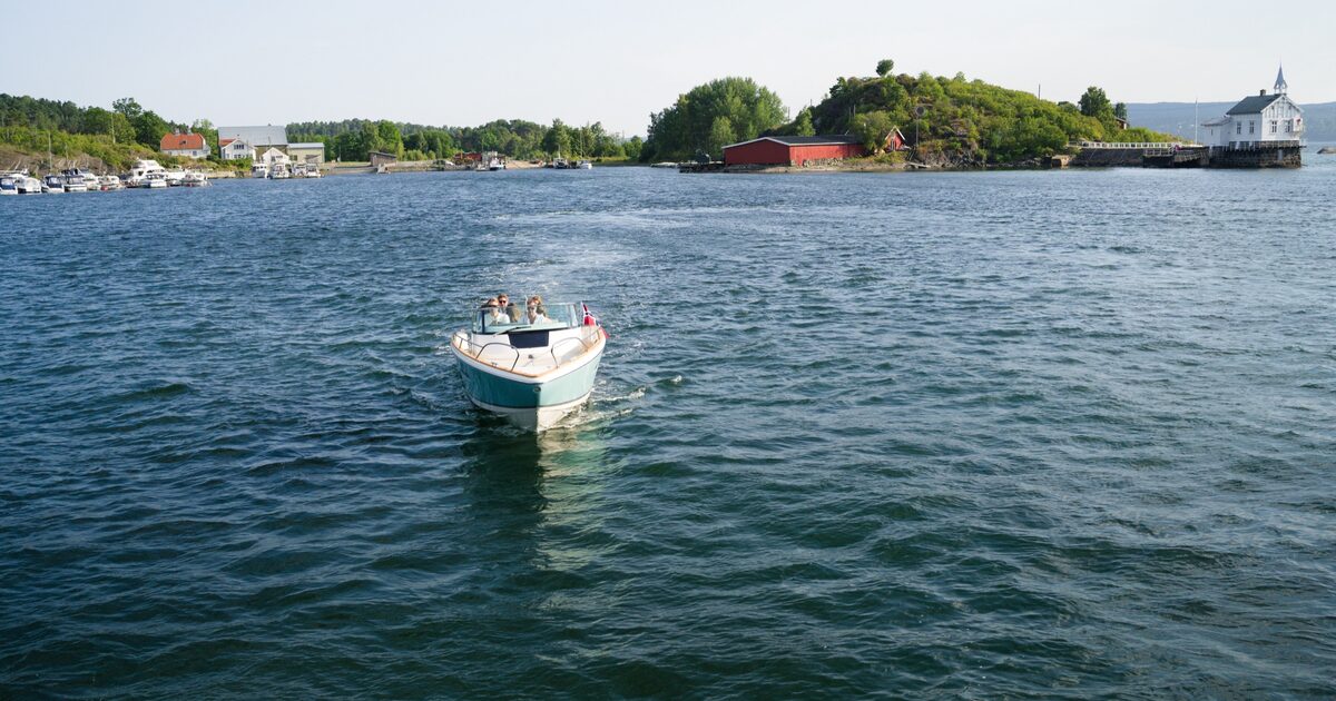 The boat passing a tall wooded island on the Oslofjord