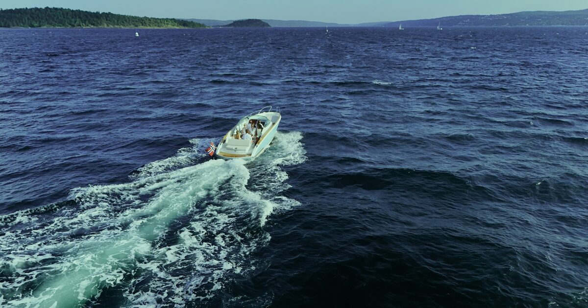 The boat's wake across green fjord water