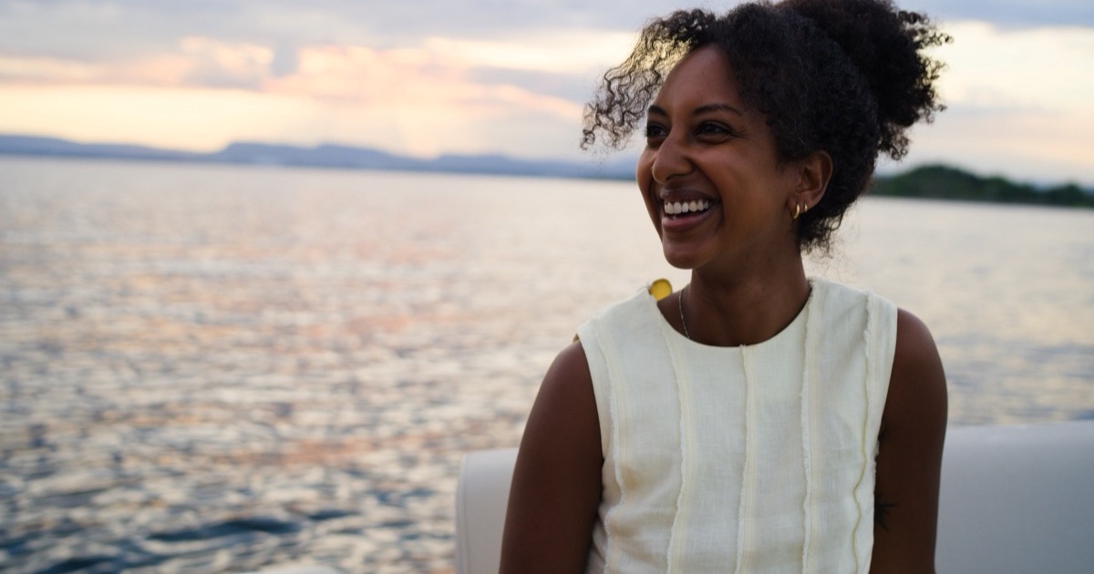 A guest laughing on deck in golden evening light over the fjord