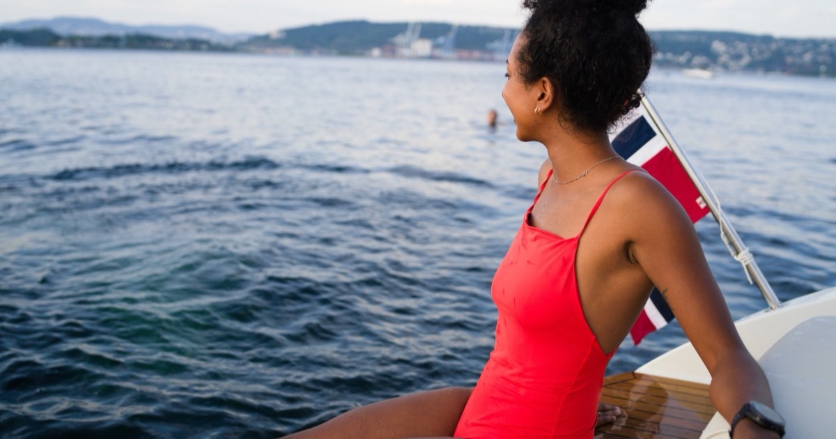 Swimmers and evening sun on the Oslo harbour promenade in summer, with the fjord and island ferries behind