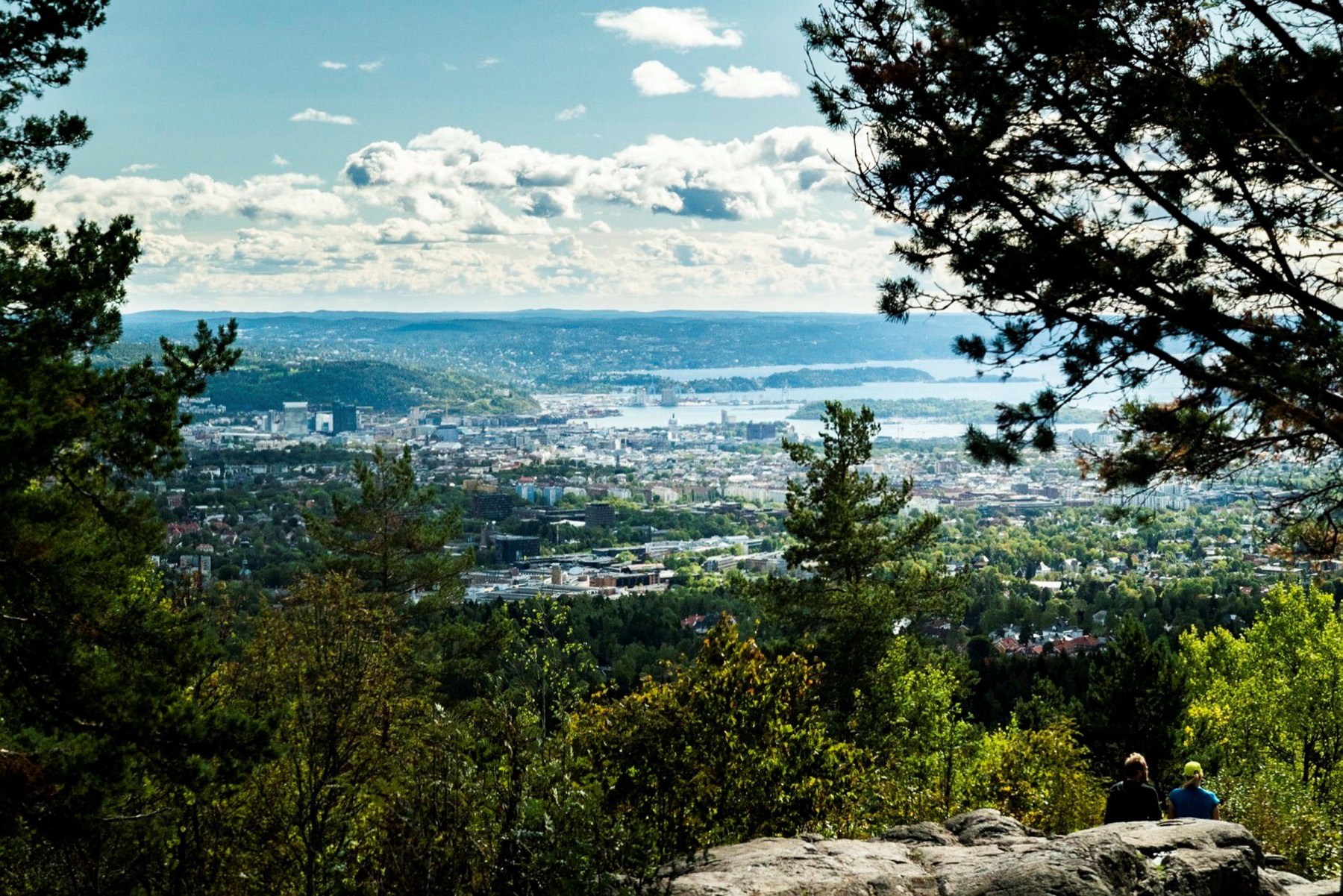 Two guests at Vettakollen viewpoint in Nordmarka, Oslo and the fjord below